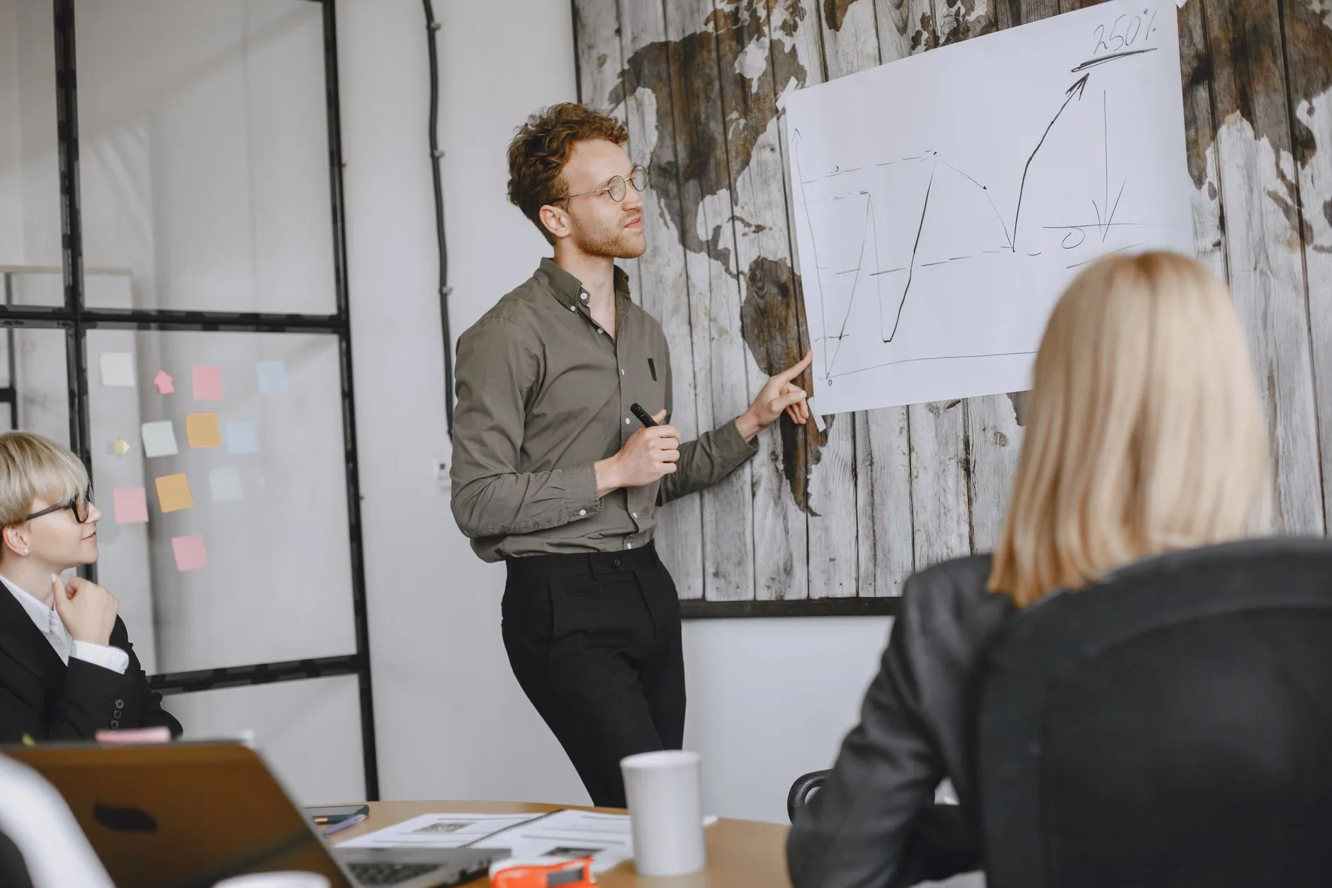 A manager presenting a performance chart to colleagues seated around a conference table in a modern office
