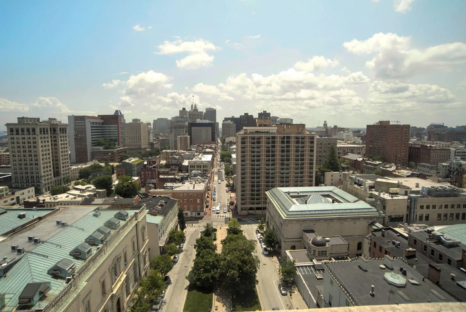 A street of brick row houses and mid-rise buildings seen from above, leading toward downtown
