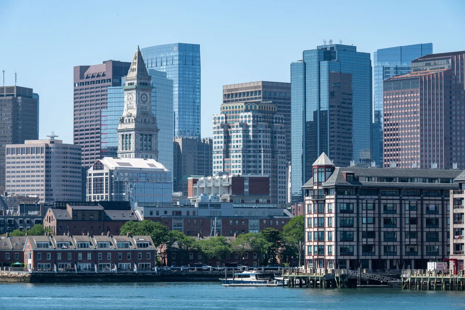 A harbor skyline with an old clock tower among glass office buildings and brick waterfront rows