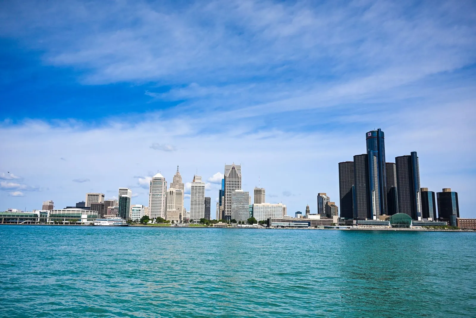 A riverfront skyline with a cluster of dark round towers across bright turquoise water