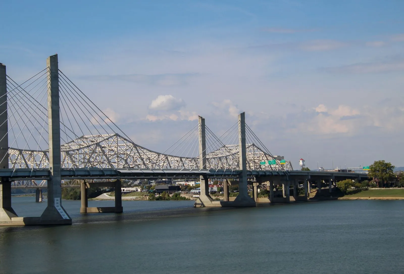 A white cable-stayed bridge crossing a wide river on a sunny day