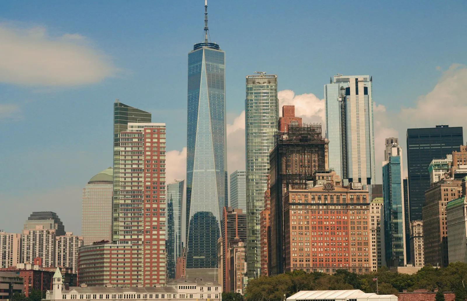 A tall tapered glass tower rising above a cluster of high-rises and older brick buildings
