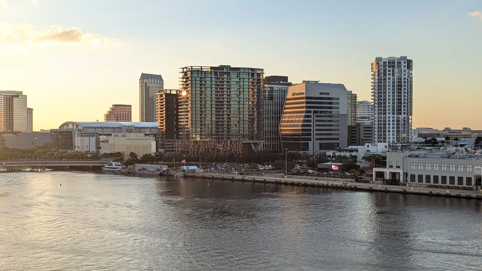 High-rise apartments and office towers along a calm river at sunset