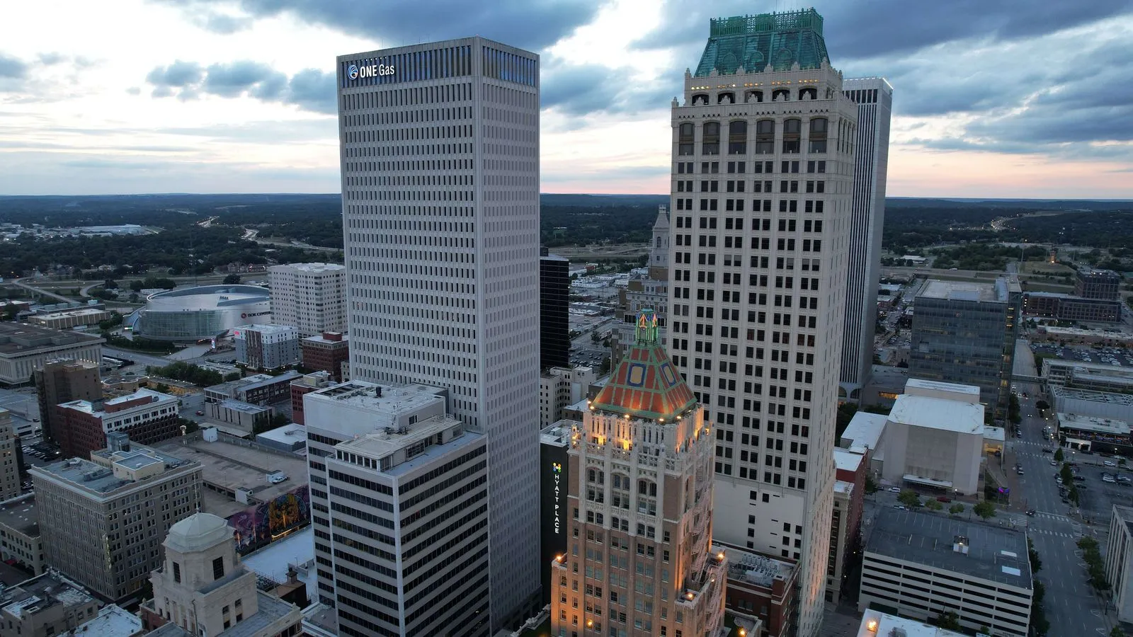 Tall office towers seen from above at dusk, an ornate older tower with a green crown in front