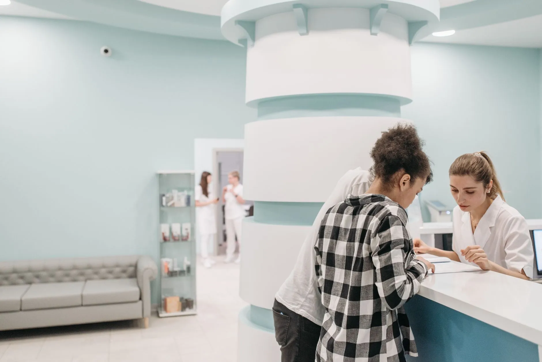 Staff at a clinic reception desk going over paperwork with two visitors