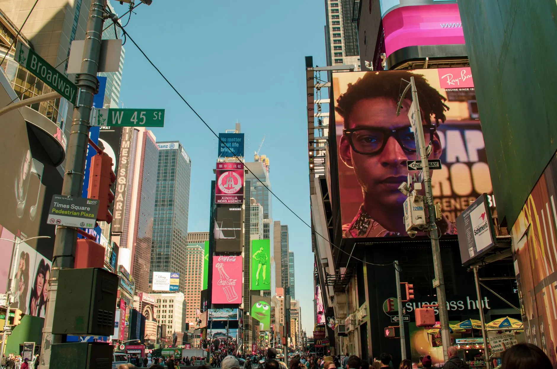Illuminated advertising billboards stacked across building faces above a busy city street