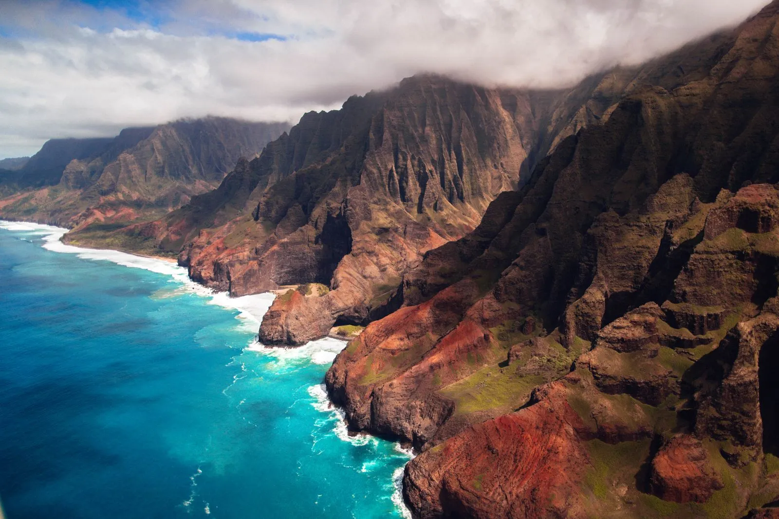 Steep green ridges and red earth plunging into turquoise surf