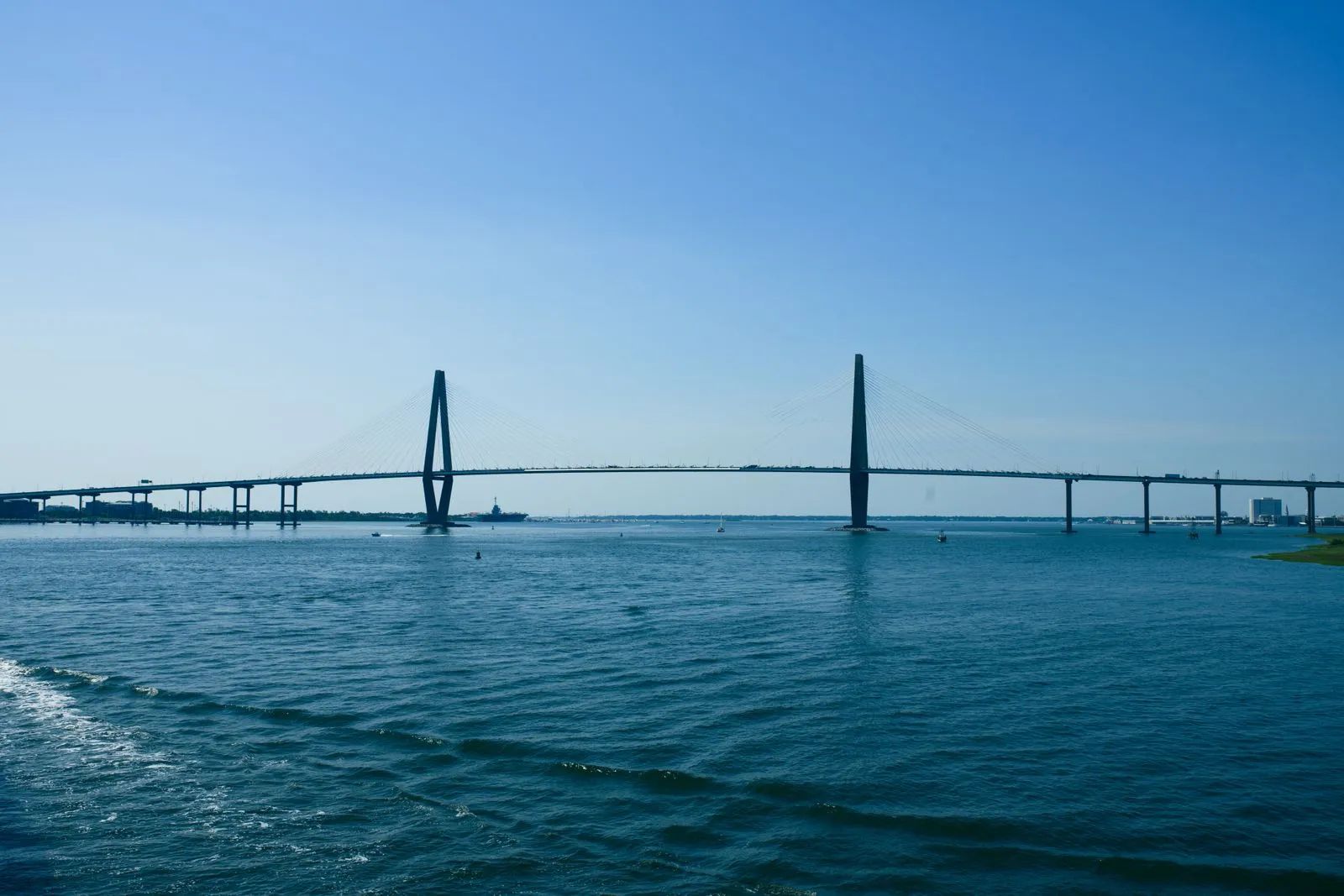 A long cable-stayed bridge with two tall diamond towers across open blue water