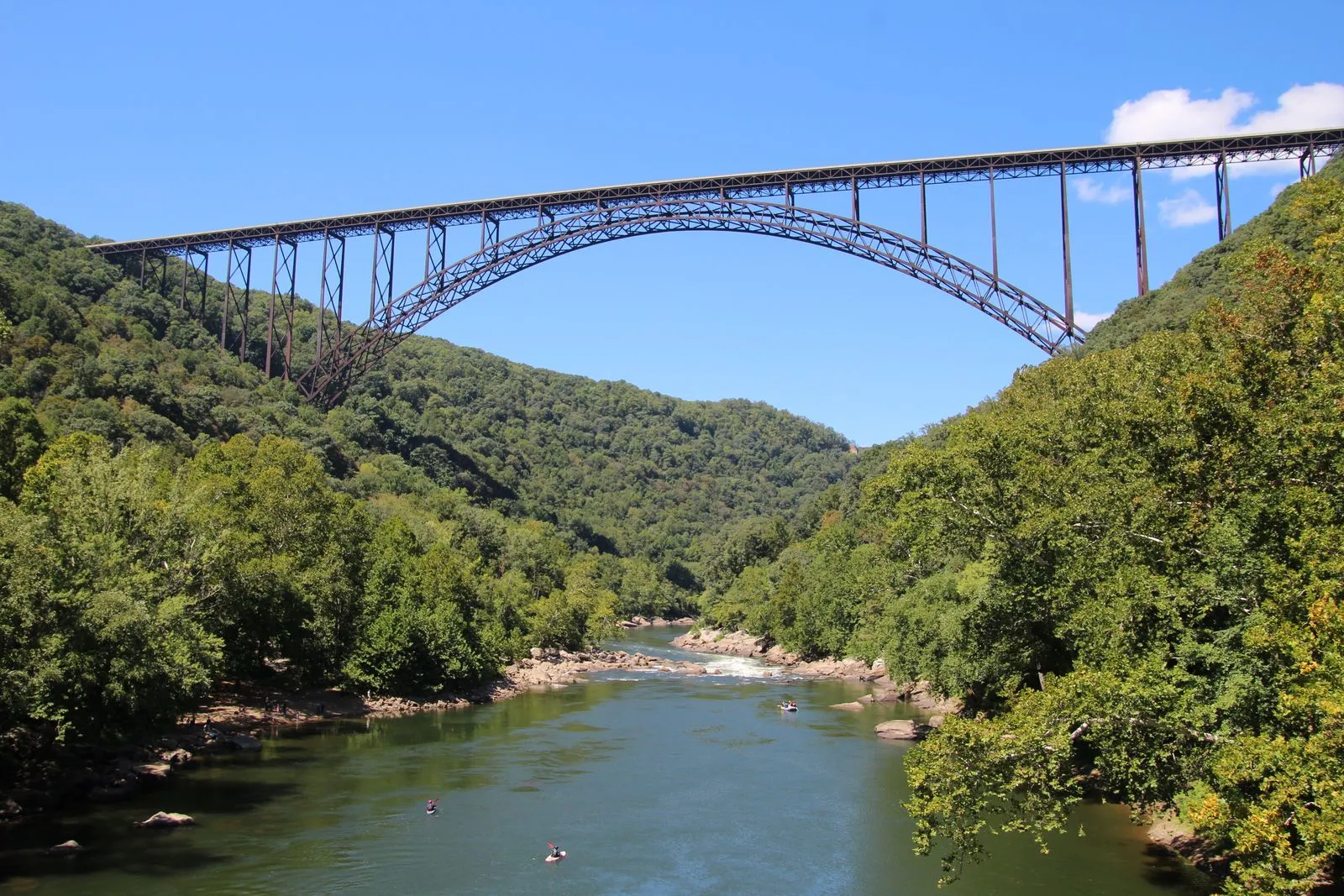 A steel arch bridge high above a forested gorge with a river at the bottom